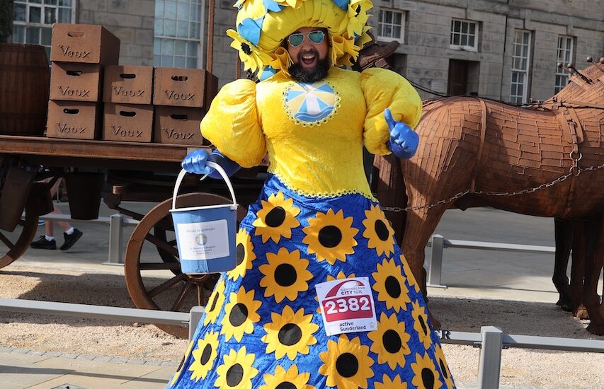 A man wearing a giant dress decorated with sunflowers.
