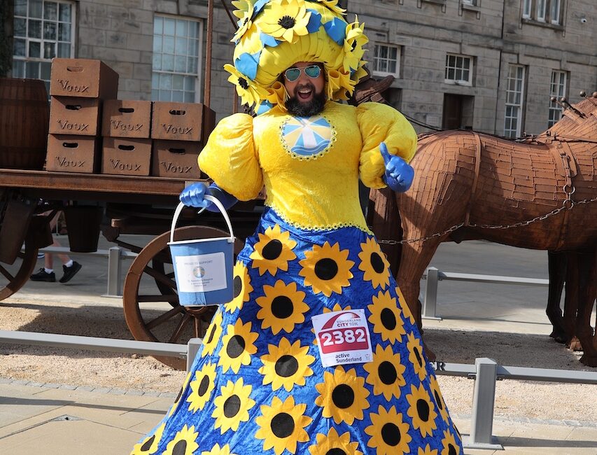 A man wearing a giant dress decorated with sunflowers.